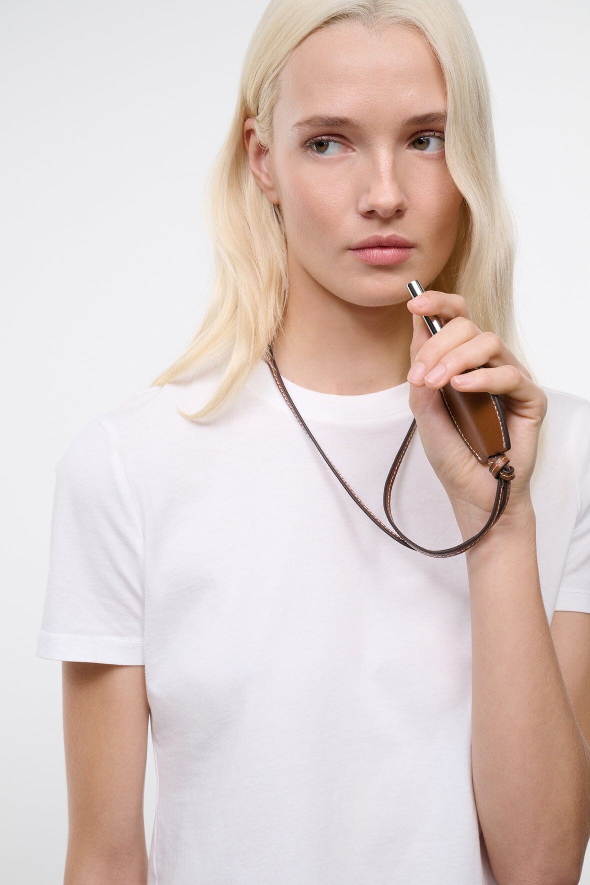 Tan-brown leather whistle pendant on cord near the neck
