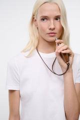 Tan-brown leather whistle pendant on cord near the neck