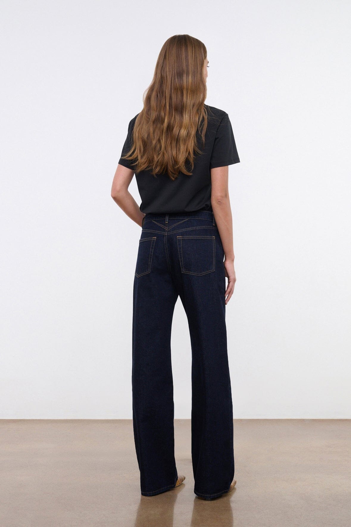 Black crew neck short-sleeve T-shirt worn with jeans.