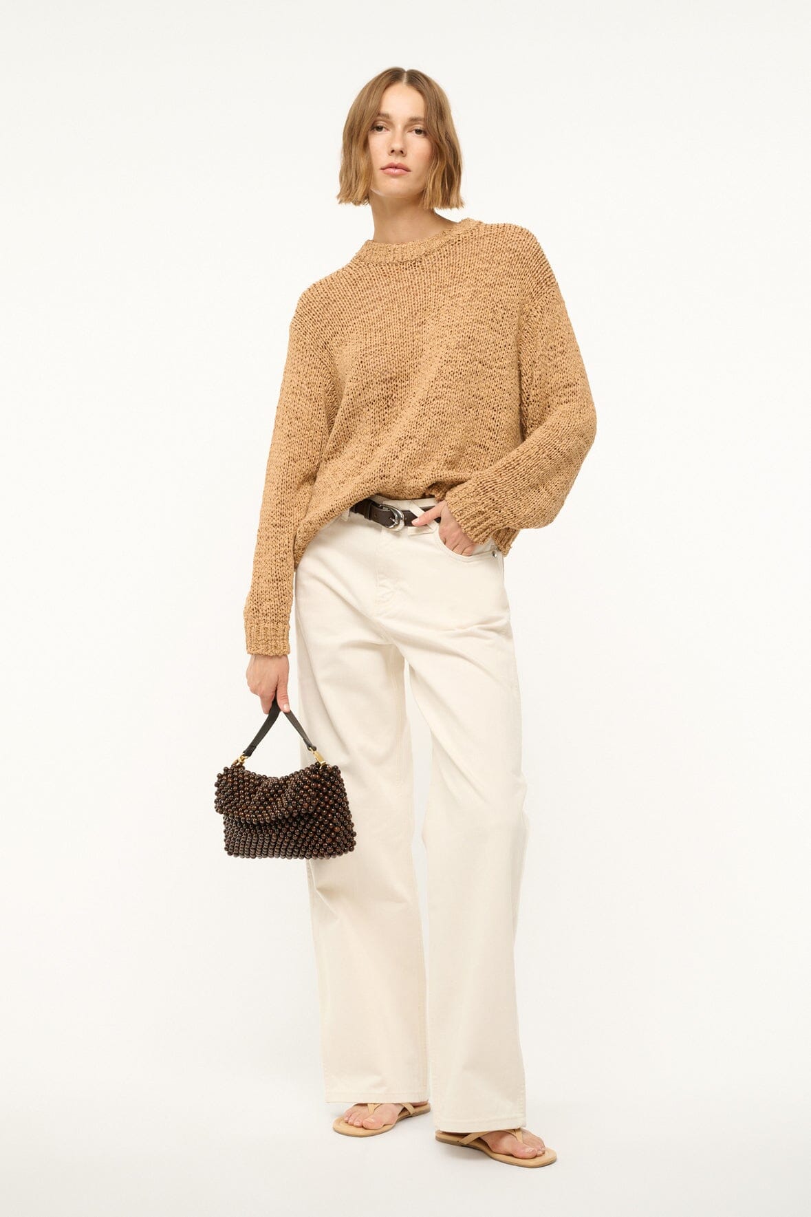Dark brown beaded shoulder bag with gold-tone chain handle, model carrying crossbody