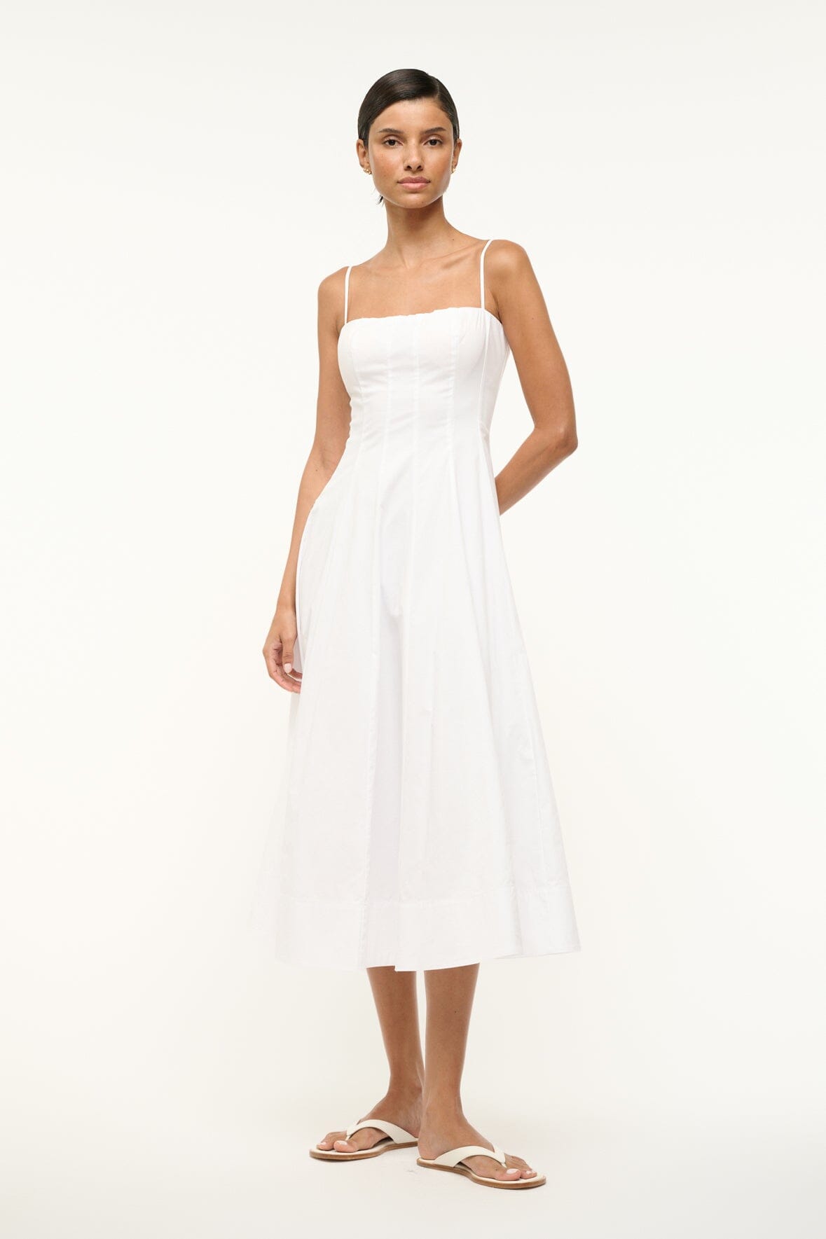 White midi dress with thin straps, structured bodice, and flared hem
