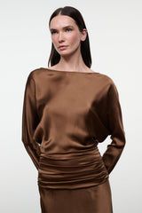 Brown silk dress with long sleeves, boat neckline, ruched waist and draped skirt