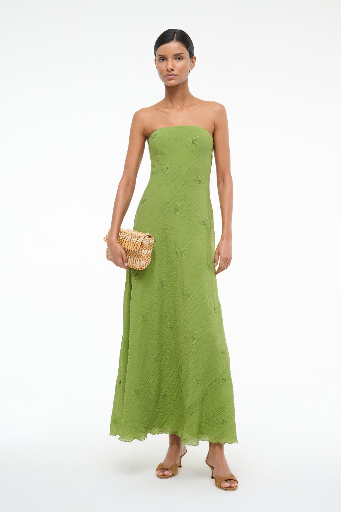 Garden green strapless maxi dress with textured finish, held with a woven shoulder bag