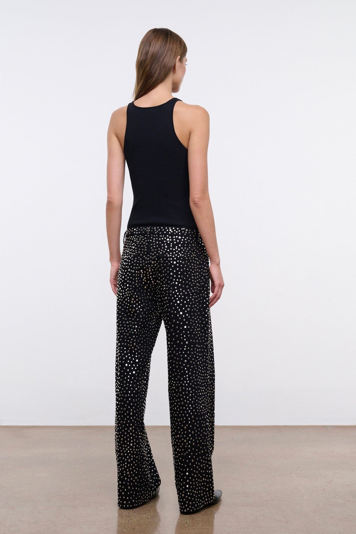 Black studded relaxed jeans on model, side view showing wide legs.