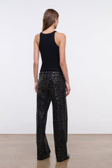 Black studded relaxed jeans on model, side view showing wide legs.