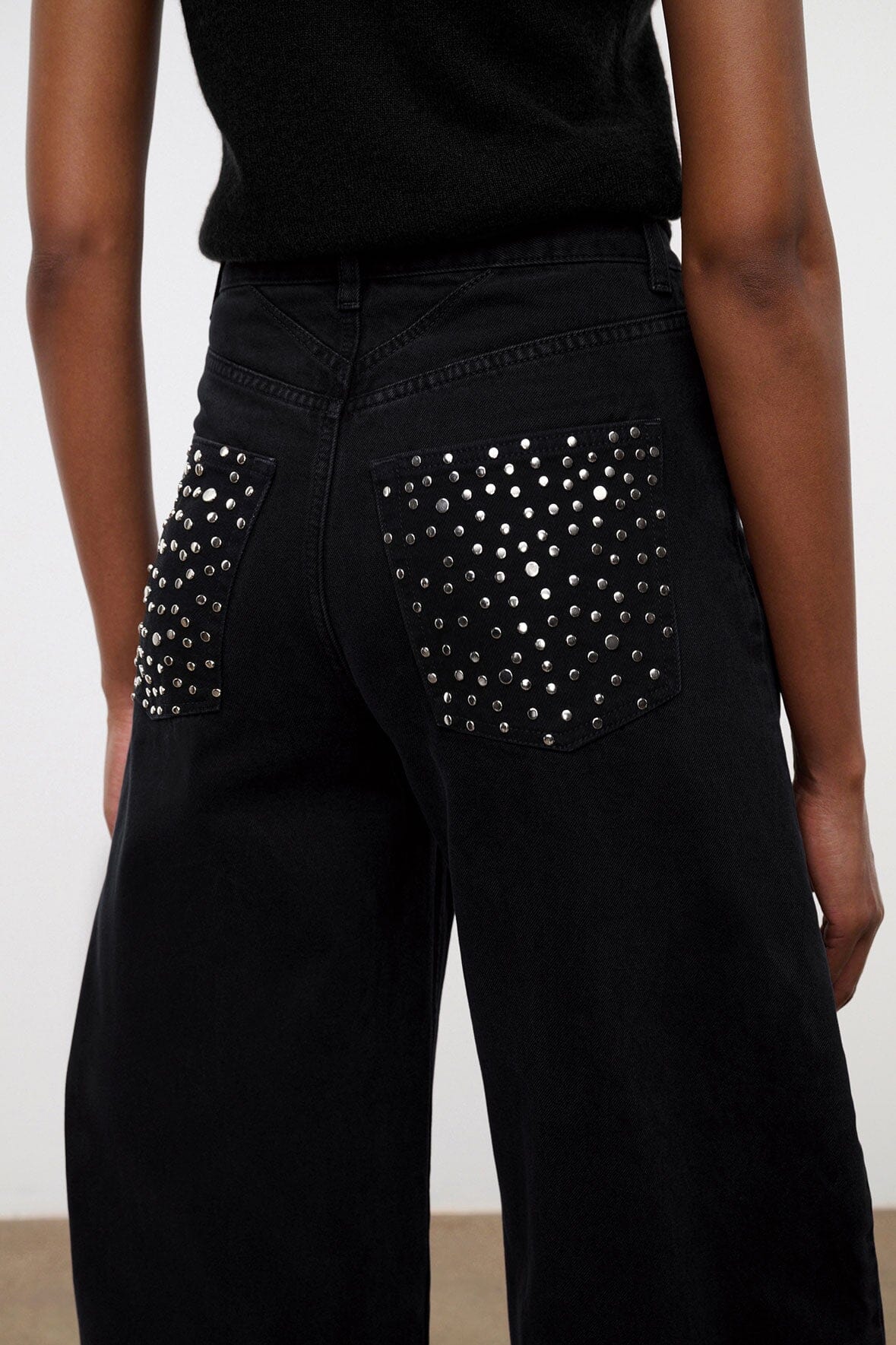 Black jeans with rhinestone-studded front pockets and high-rise waistband