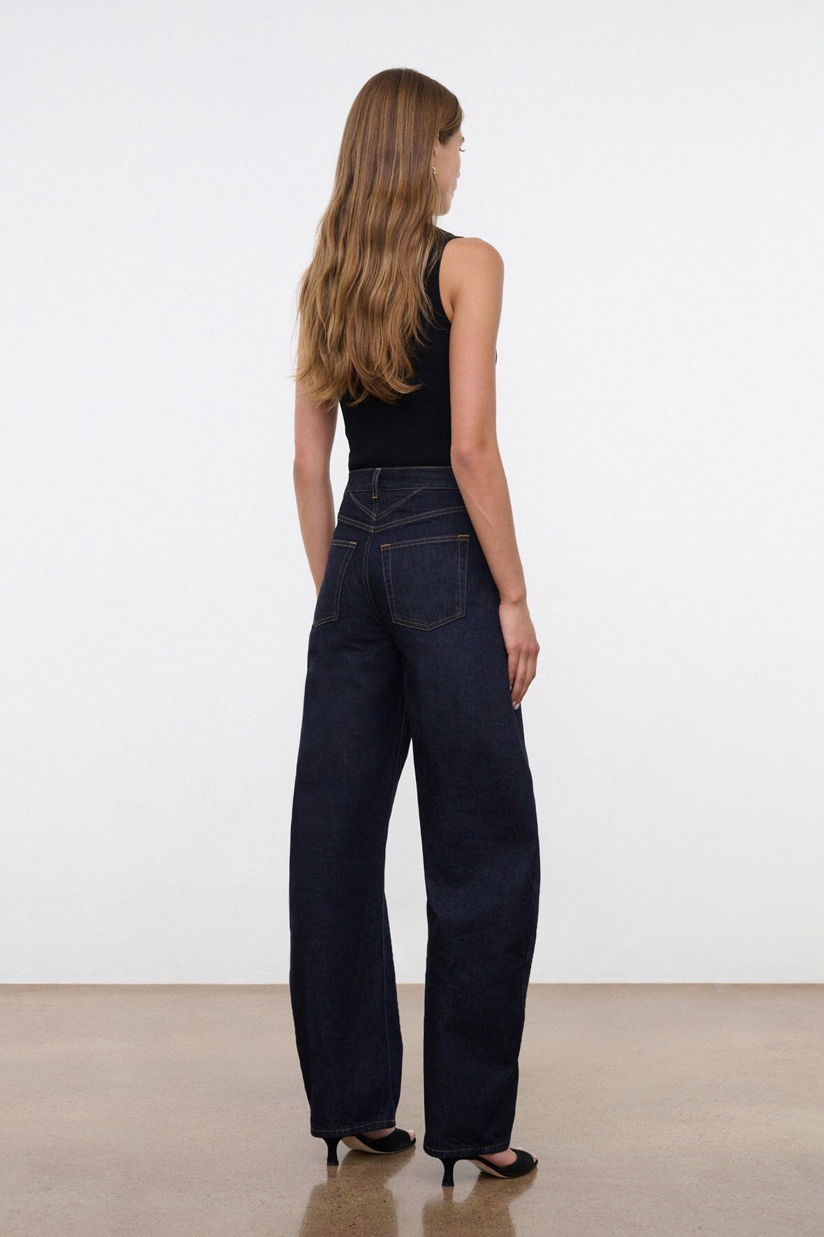 Indigo barrel-leg jeans worn by model, side view