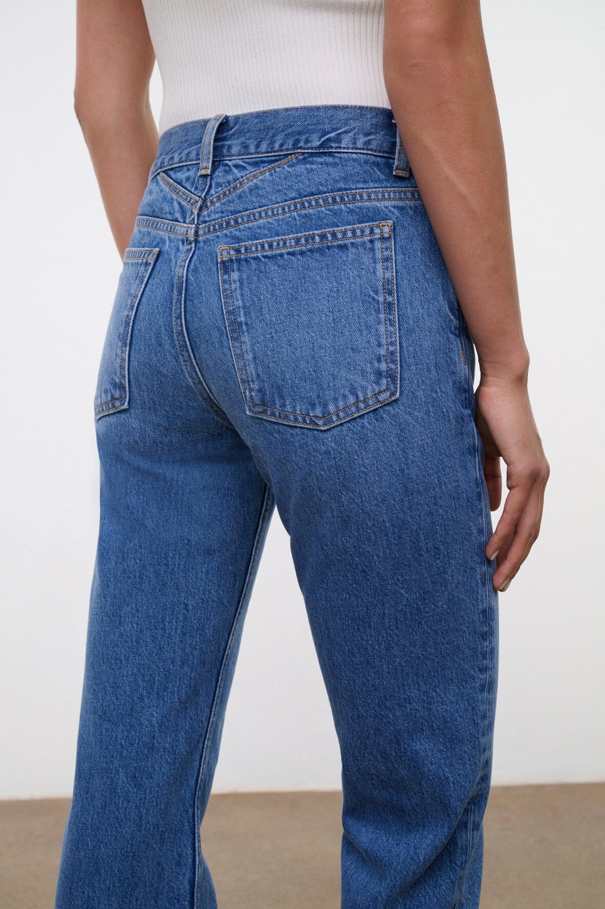 Vintage wash straight jeans on model, mid-blue denim with front pockets and seams.