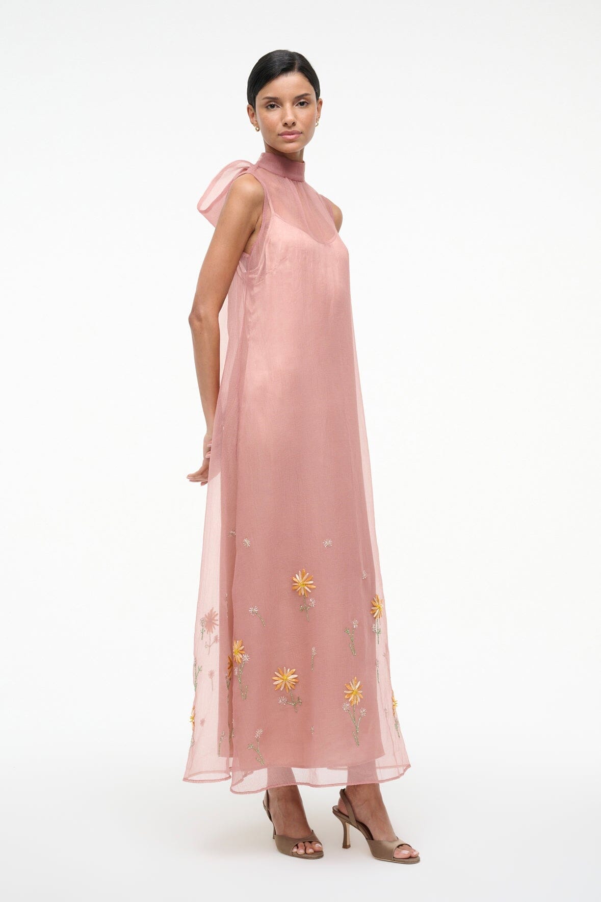 Heeled sandals under a blush sleeveless sheer dress with small yellow flower embroidery