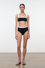 High-rise bikini bottom, black with white waistband trim, full-length front view model.