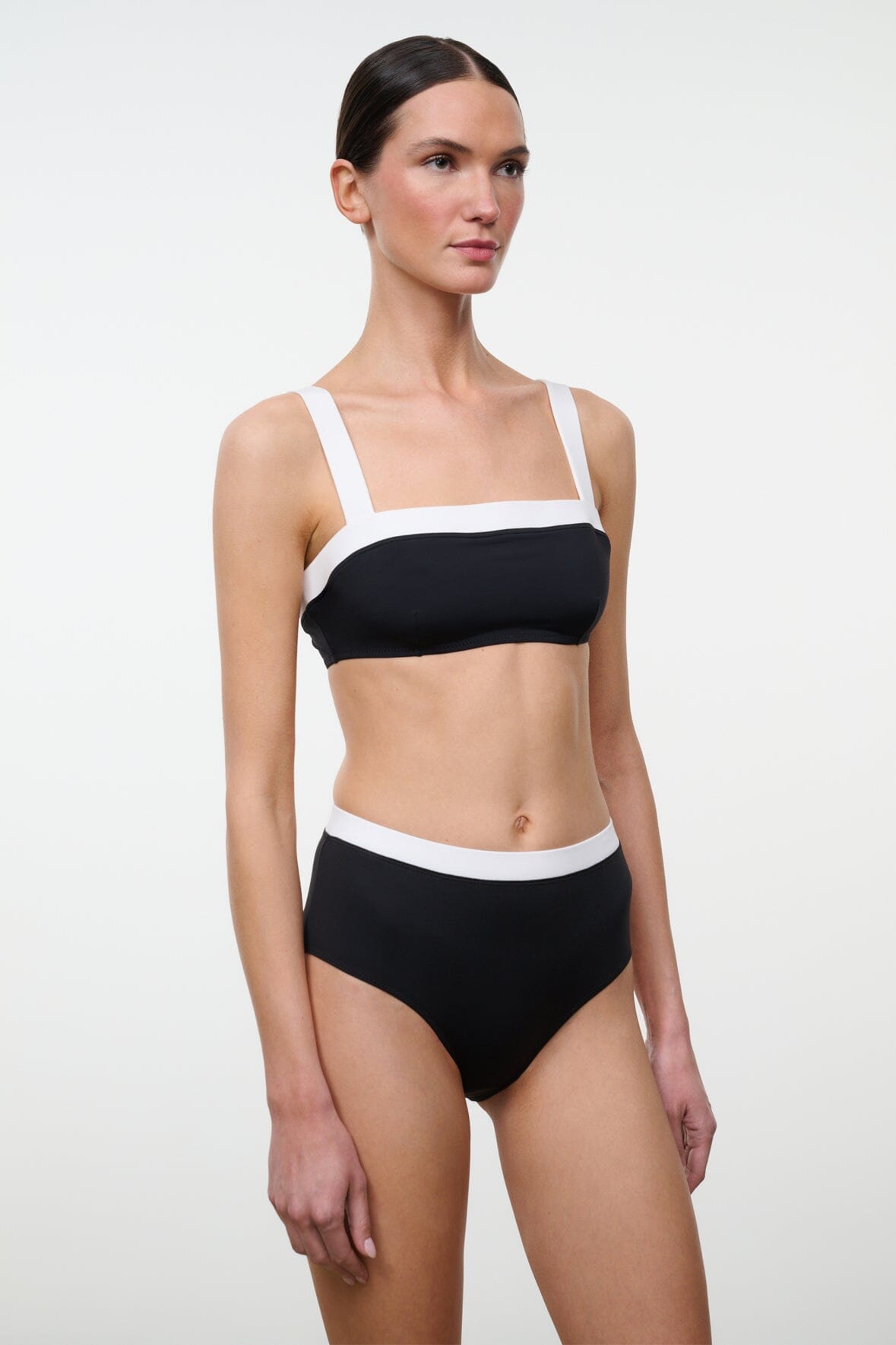 High-rise bikini bottom, black with white waistband trim, front view on model.