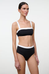 High-rise bikini bottom, black with white waistband trim, front view on model.