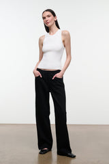 A woman modeling a white sleeveless ribbed tank top and black wide-leg trousers against a clean white studio background.