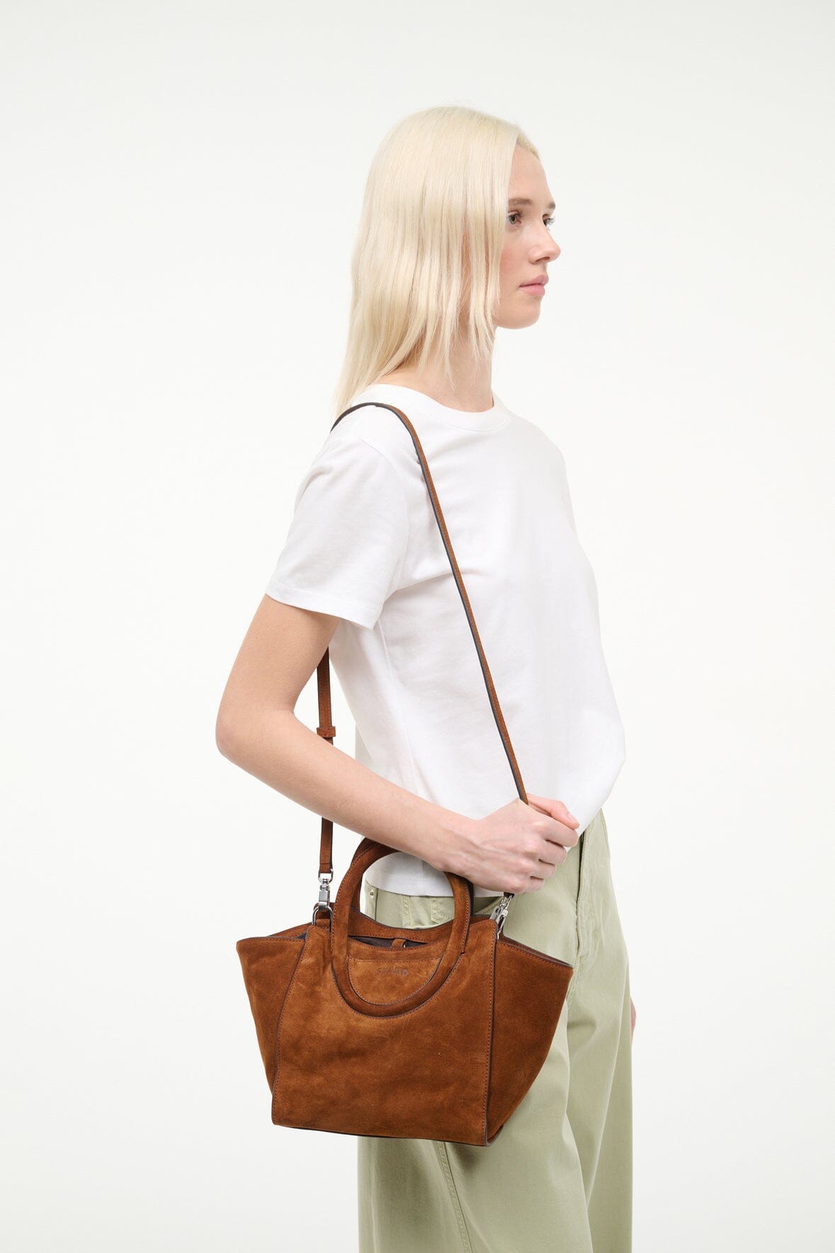 Tabac suede mini tote bag on model shoulder with stitched handle edges