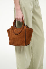 Tabac suede mini tote bag held at side, showing front panel and handles
