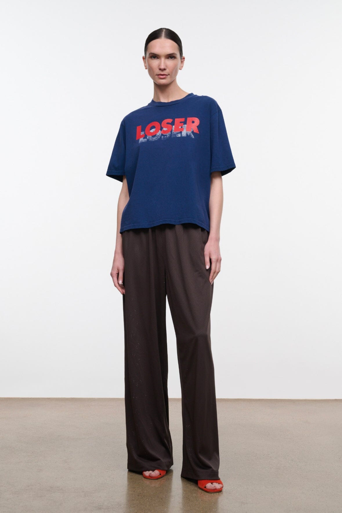 Blue relaxed tee with red 'LOSER' logo, styled with dark wide-leg pants