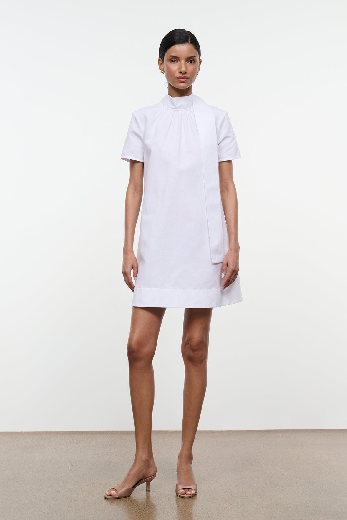White mini dress with high neck and short sleeves, straight hem.