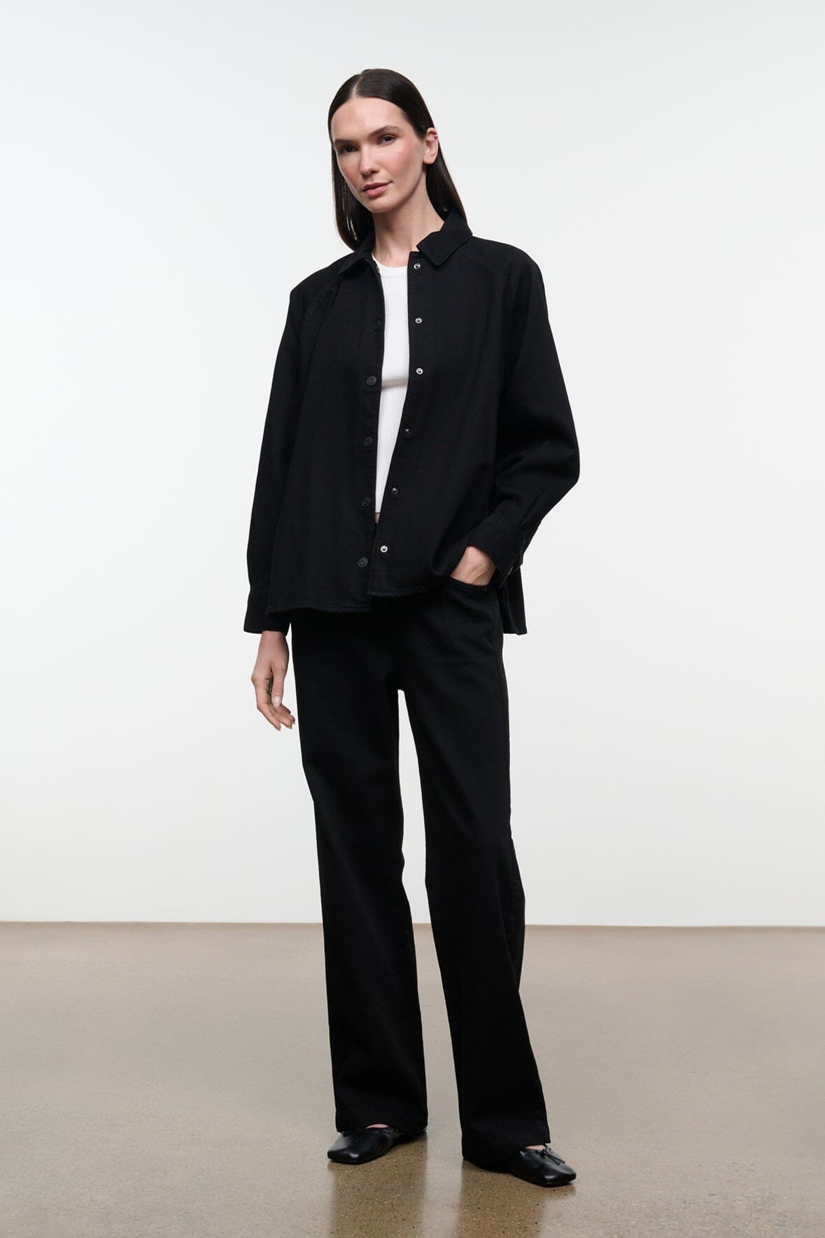 Black shirt jacket with stand collar and button front, long sleeves; front three-quarter view.