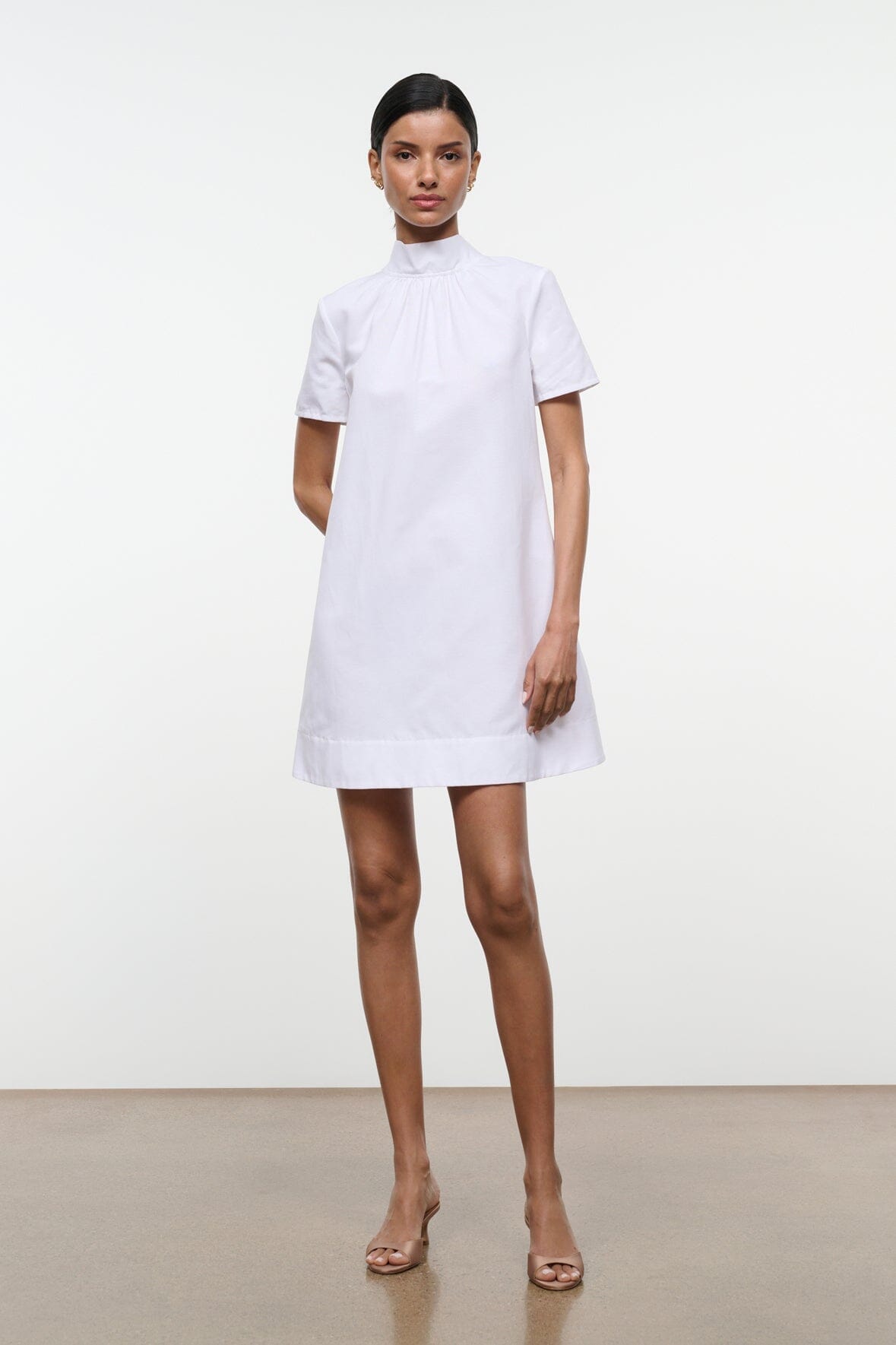 White mini dress with high neck, short sleeves, and gathered collar detail