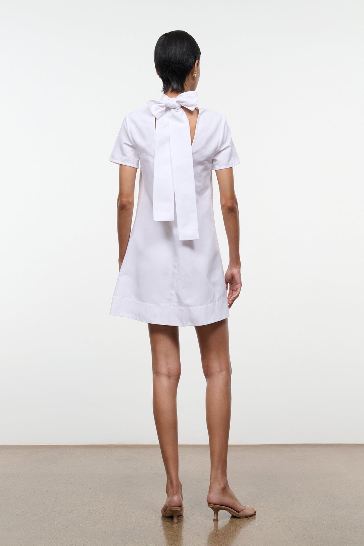 White mini dress with tied back bow at the neck and short sleeves