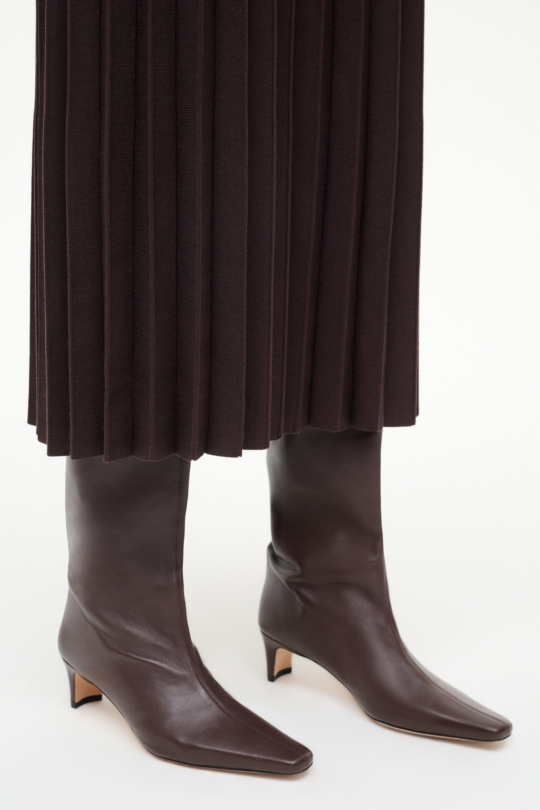 Pair of espresso brown tall heeled boots with pointed toe and stacked heels