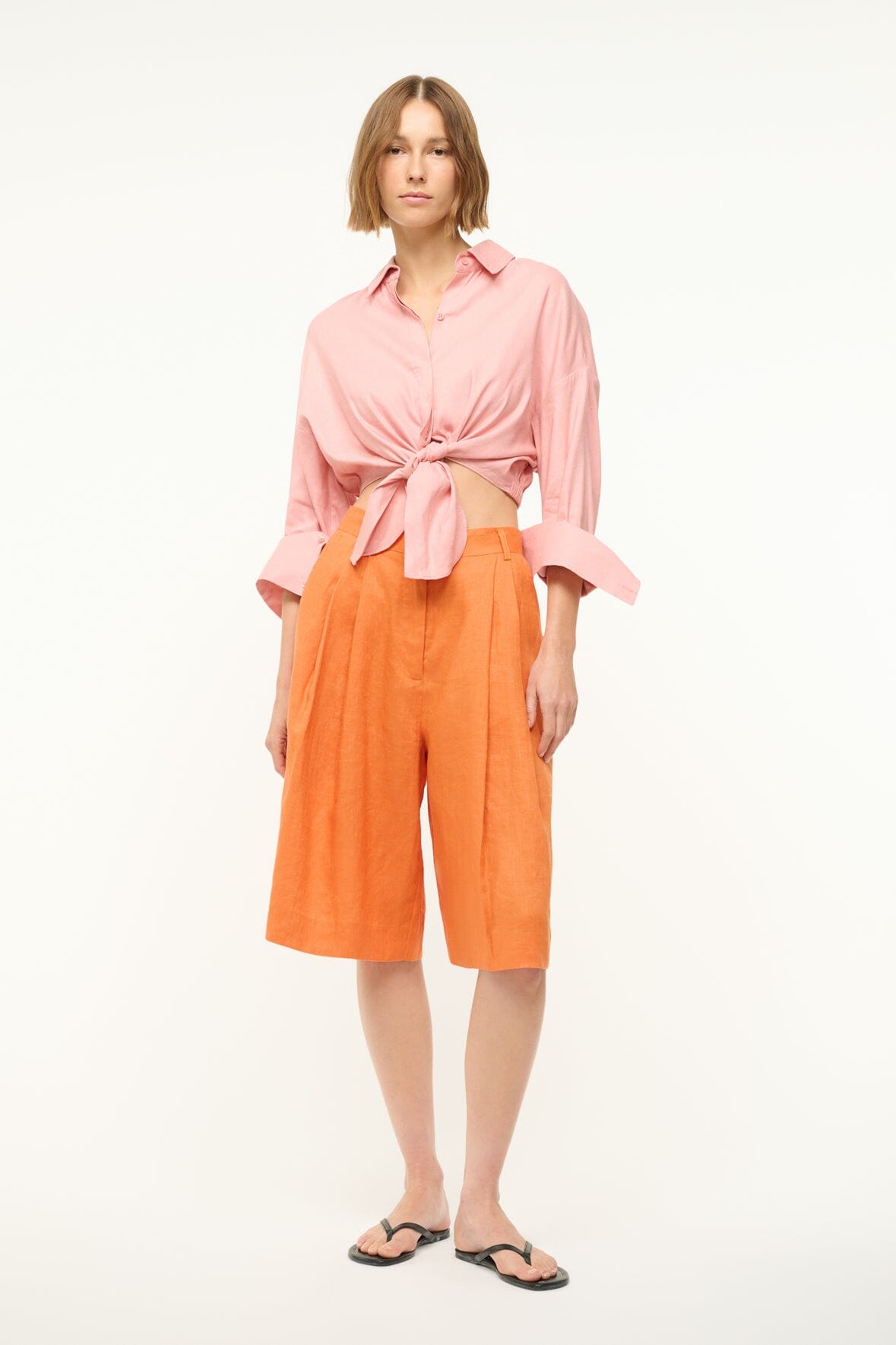 Faded blush linen button-up top with long sleeves rolled to cuffs and tied waist