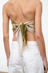 Silk scarf close-up: olive-and-gold abstract print knot at back waist