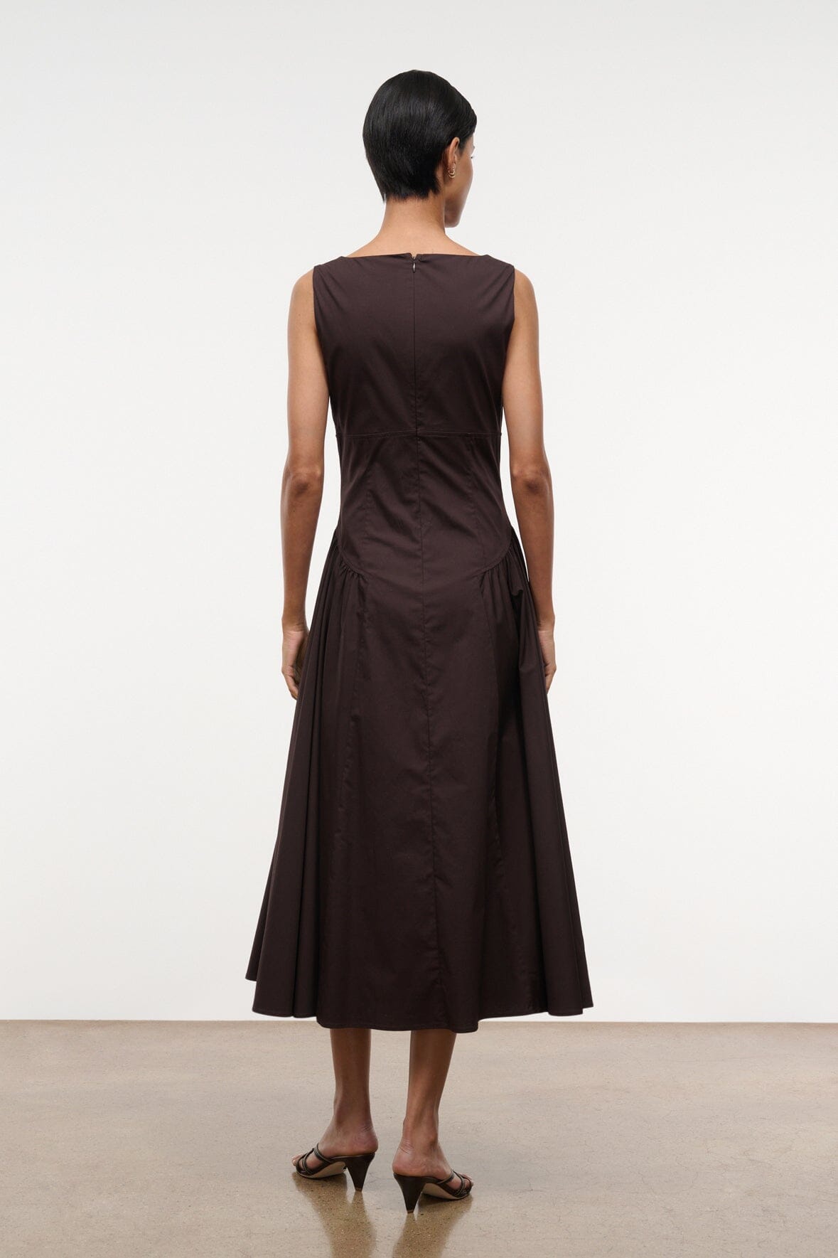 Brown sleeveless midi dress, back view with ruched waist and full flared skirt.