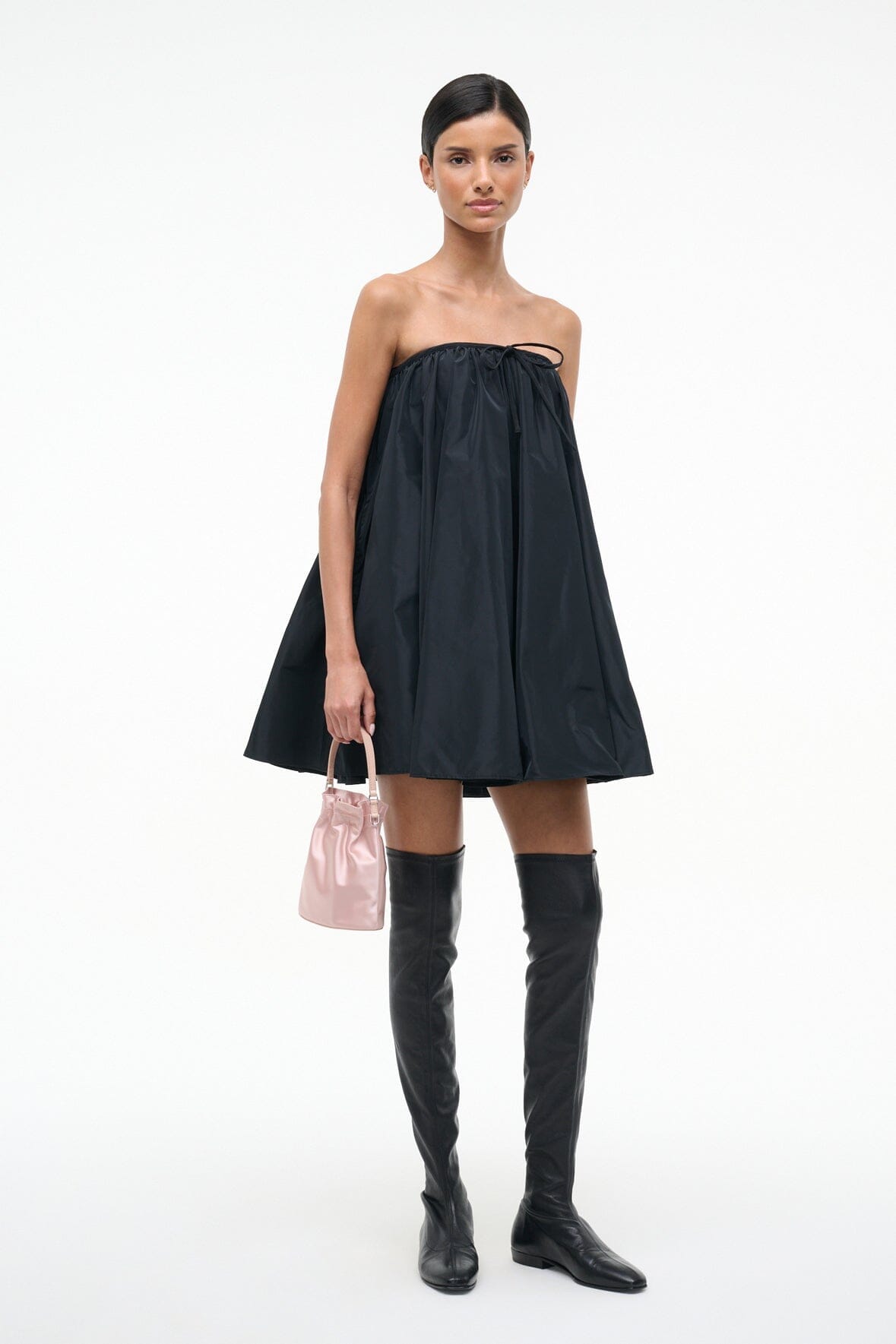 Blush mini handbag with short handle, held in hand.