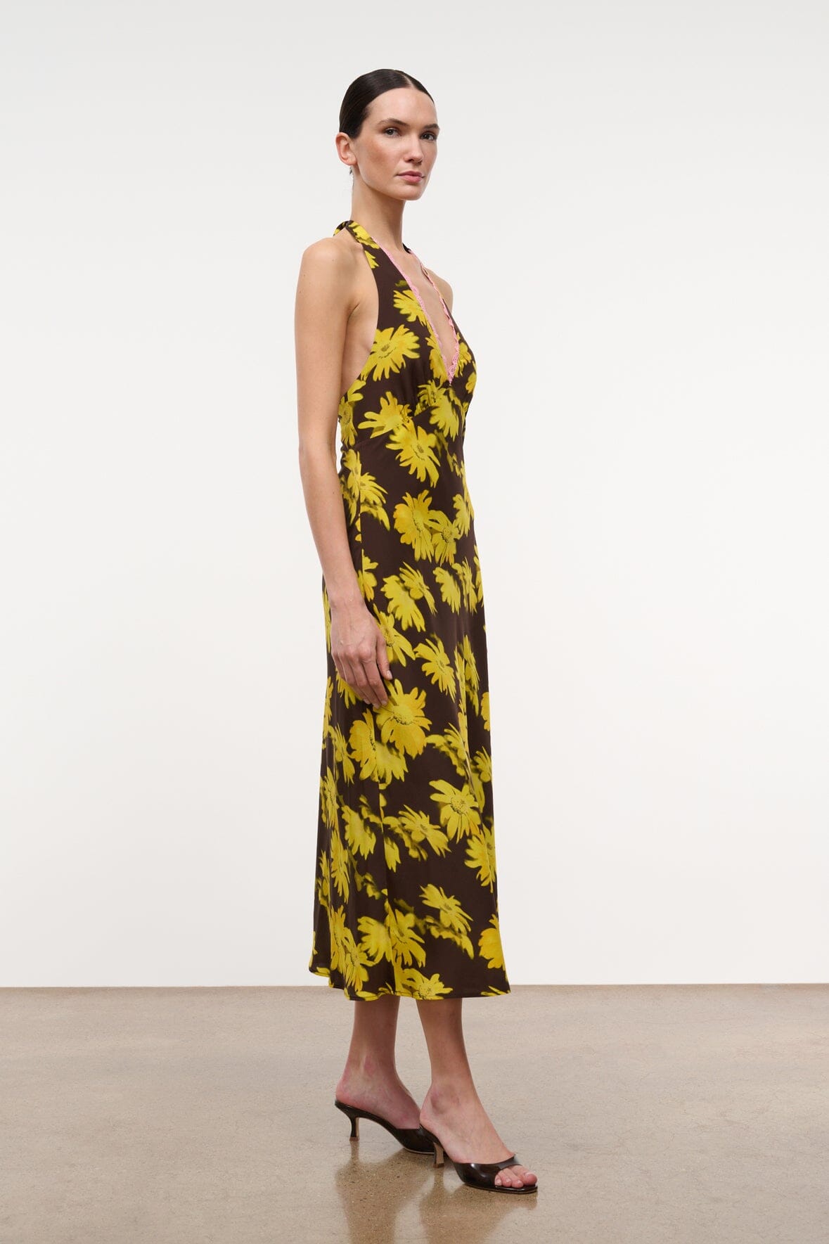 Sleeveless midi halter dress with yellow daisy print on dark background and deep V.