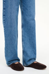 Shearling ballet flats on feet under cuffed blue jeans
