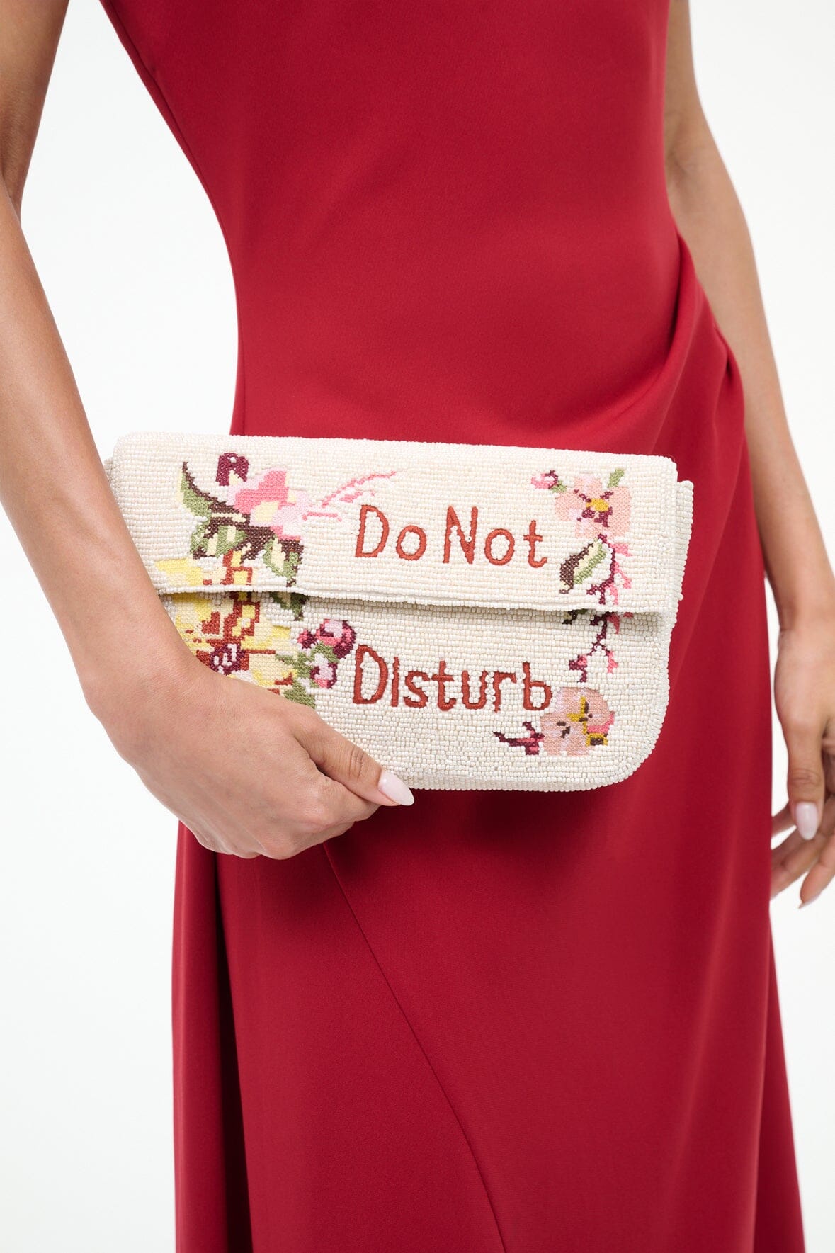 Close-up of cream tweed bag with red “Do Not Disturb” embroidery