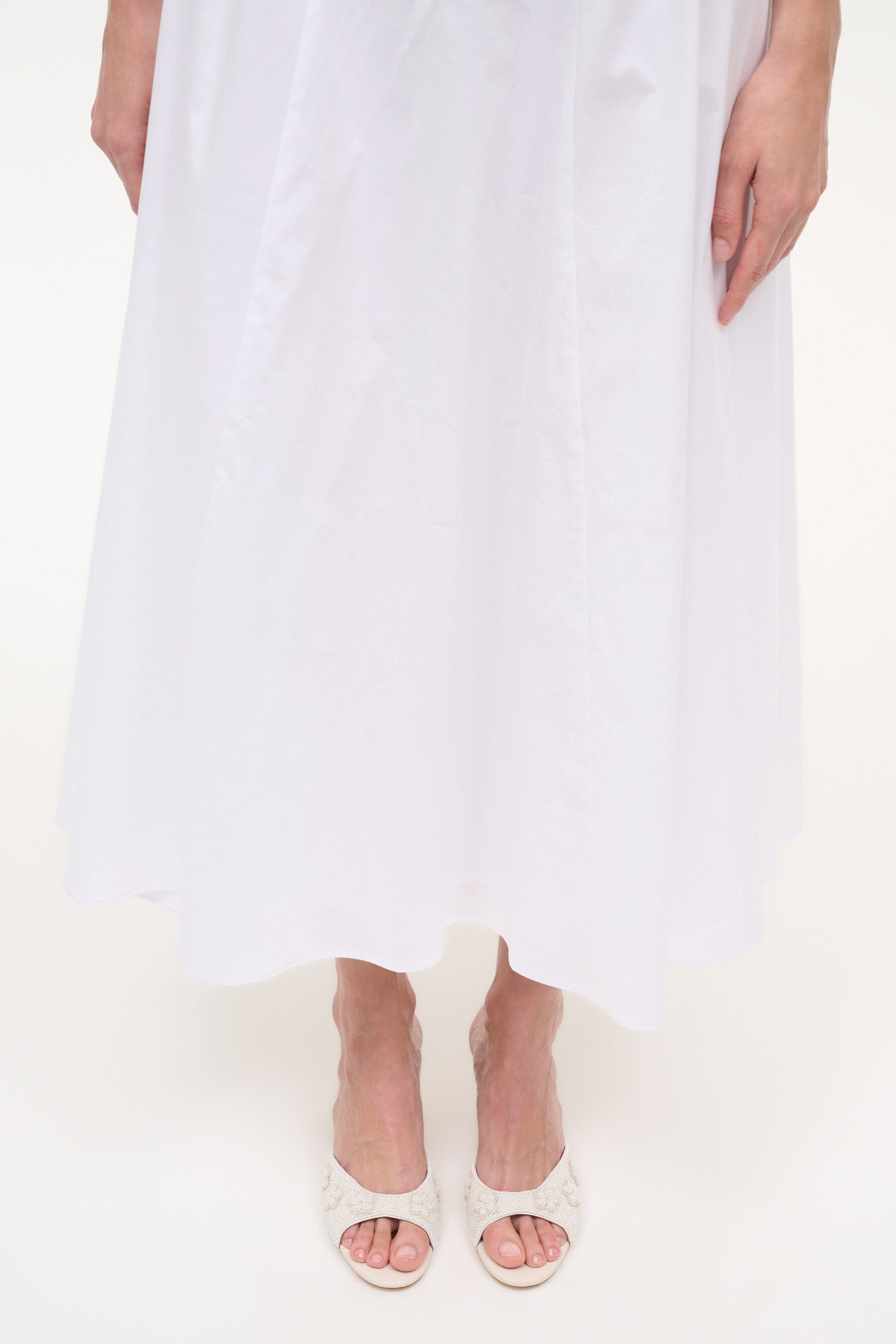 White open-toe mule sandals with textured upper and mid-height heel on legs