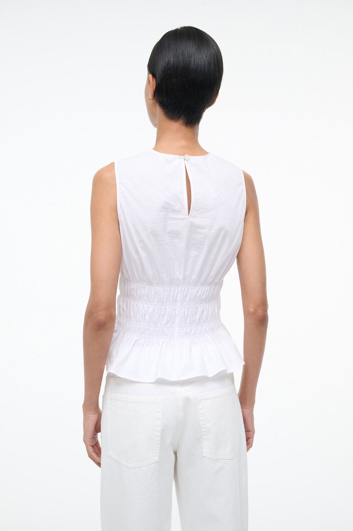 White sleeveless peplum top with back keyhole tie and smocked waist ruffle hem