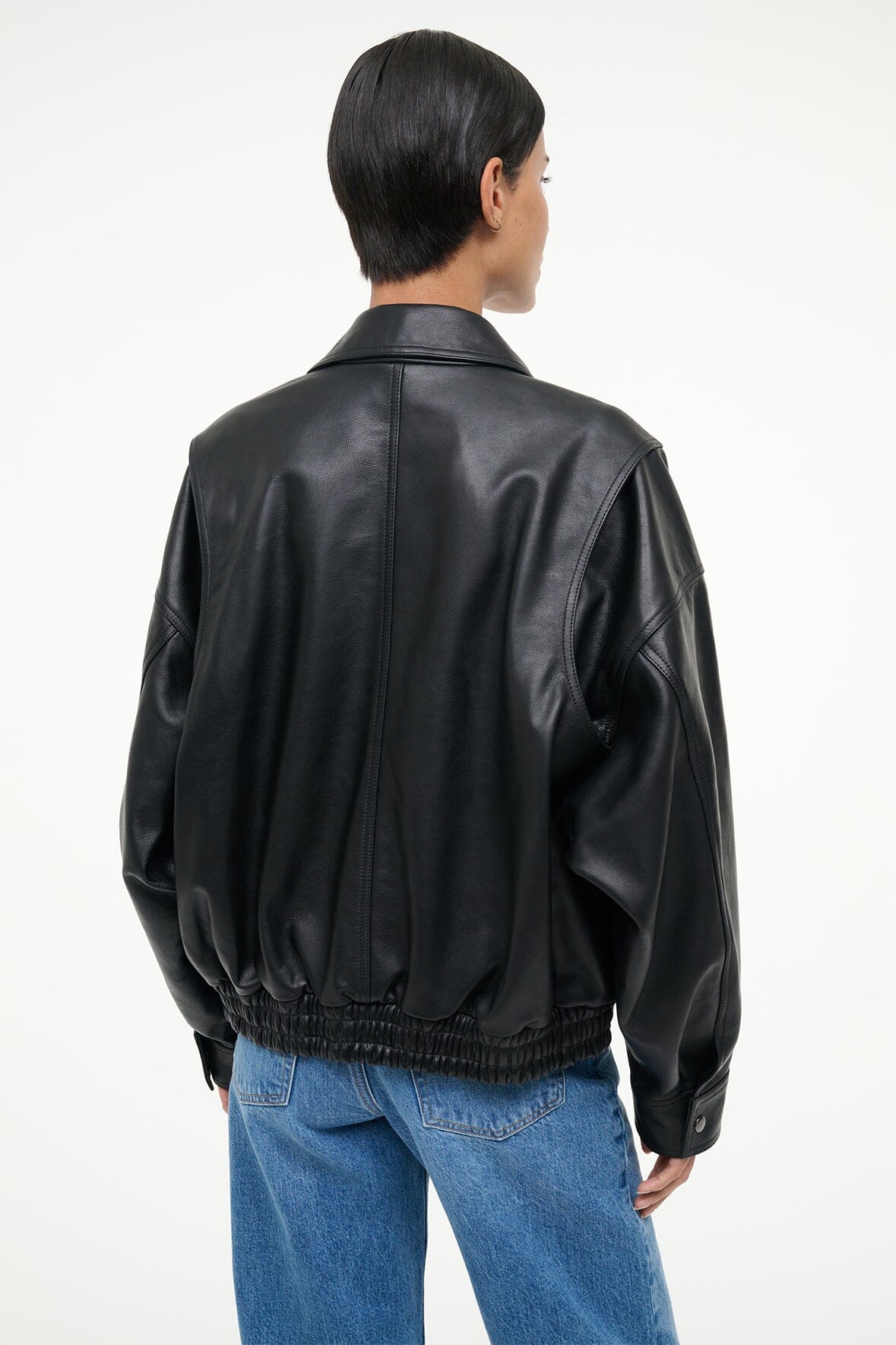 Back view of black leather bomber jacket with ribbed hem and zippered sleeves