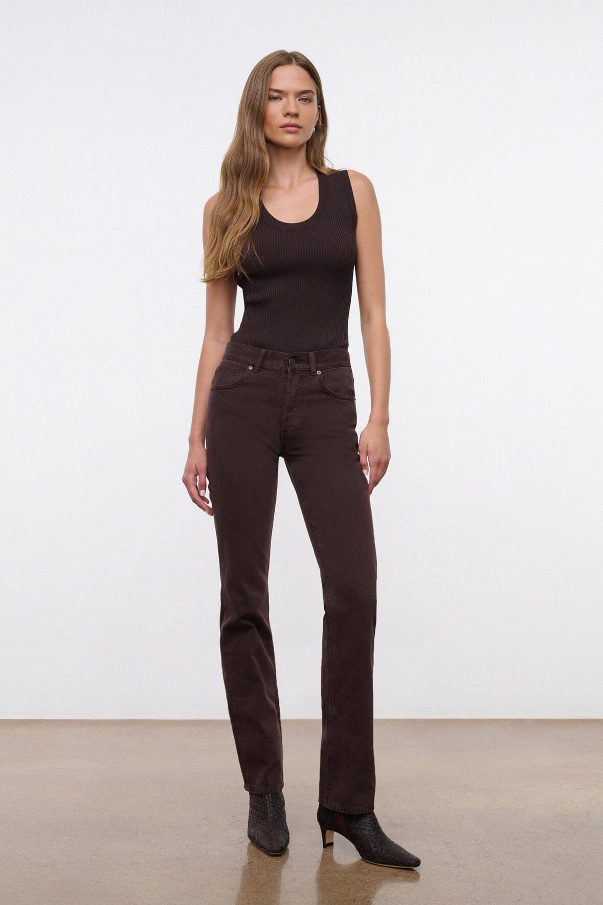 Dark brown straight jeans on model, centered front view