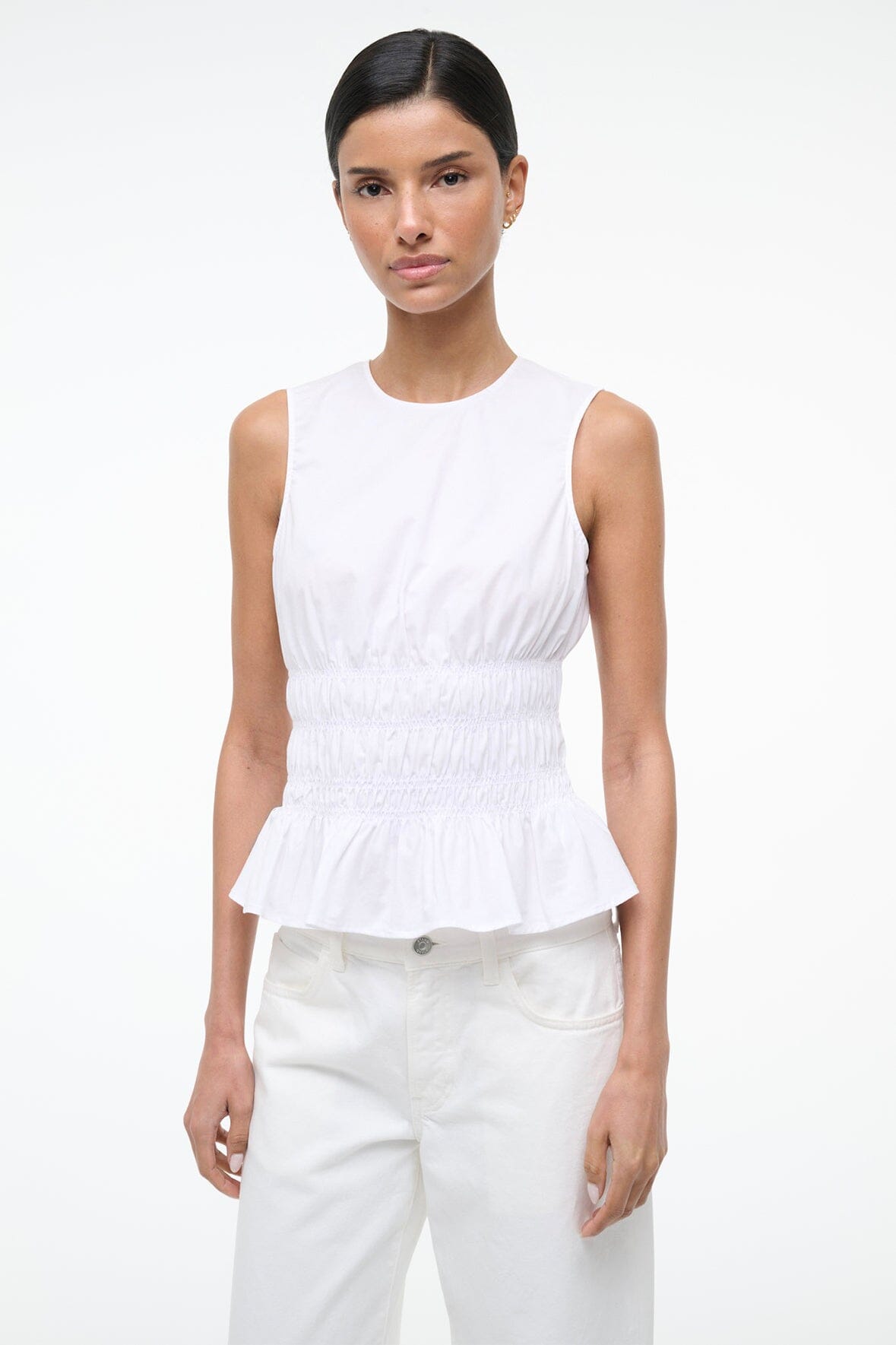 White sleeveless peplum top with round neckline and smocked waist, layered ruffle hem