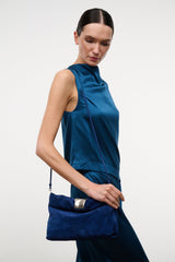Cobalt suede cuff clutch with silver-tone front clasp, held at side