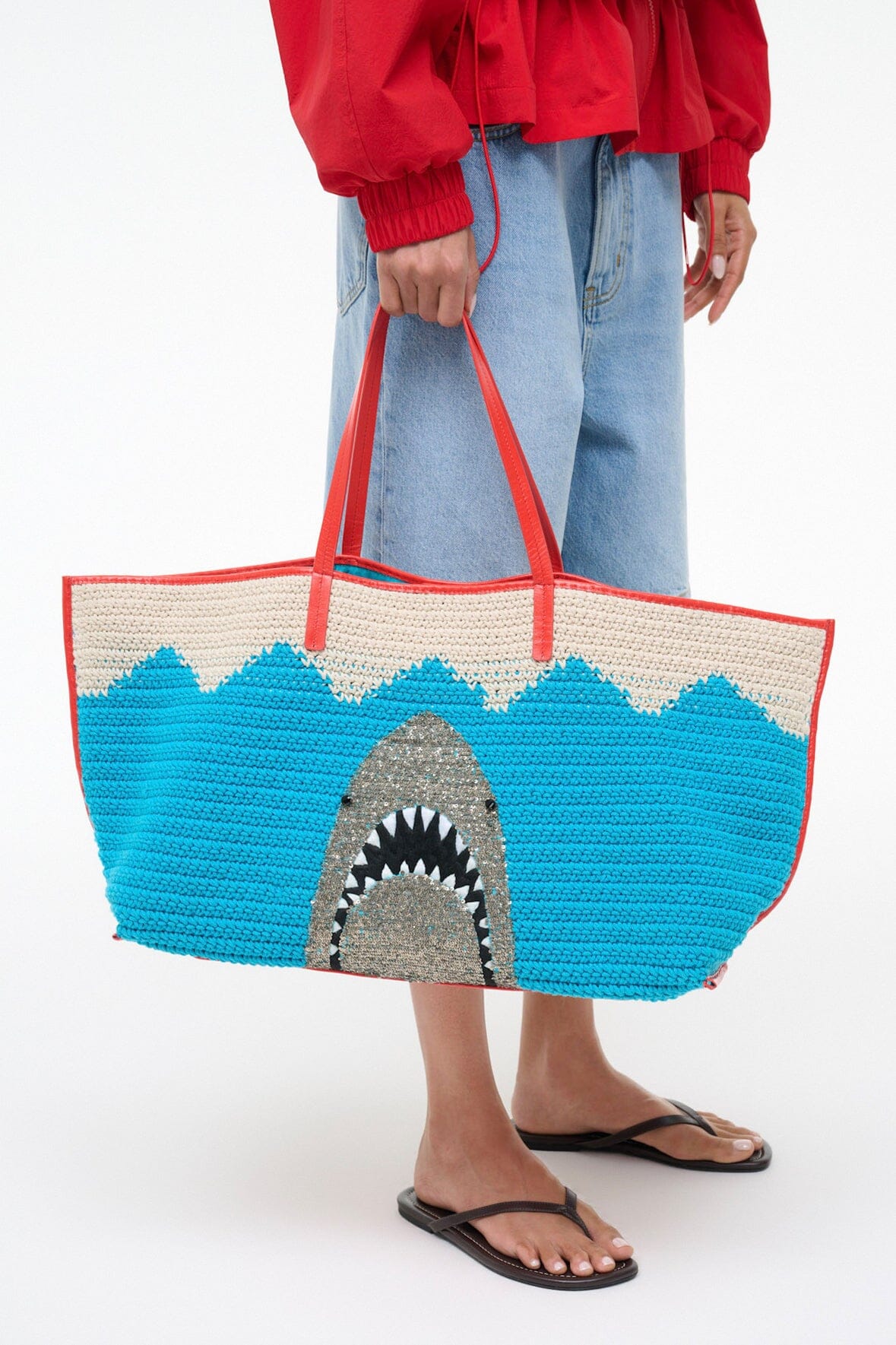 Woven tote bag with blue and natural stripes and shark-mouth graphic, red handles