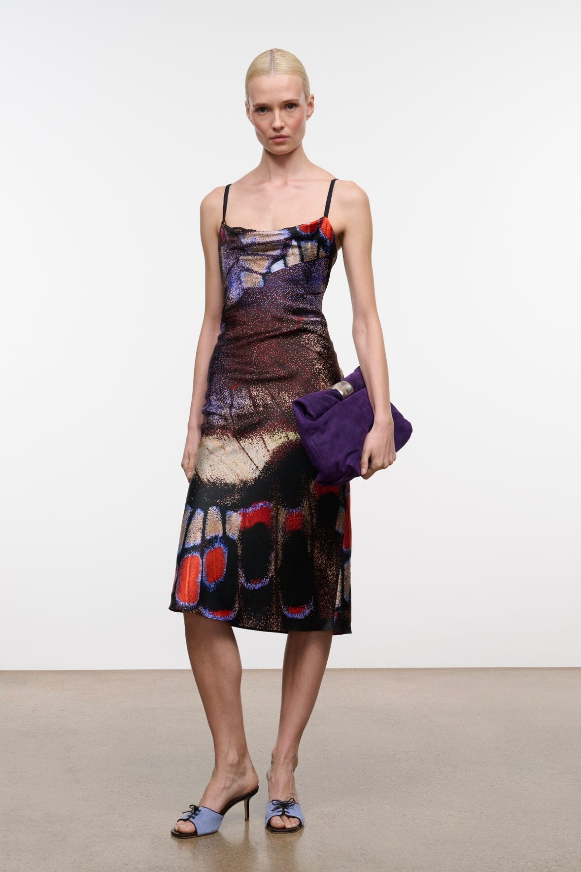Silk midi dress with spaghetti straps, draped cowl neckline, butterfly print; purple clutch