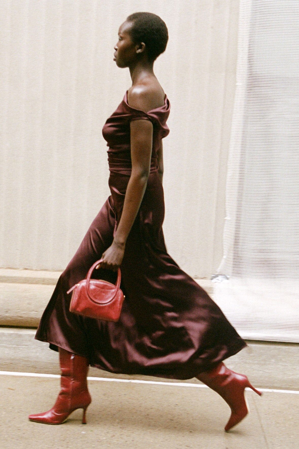 Merlot satin off-shoulder midi dress in side profile, flowing gathered skirt.