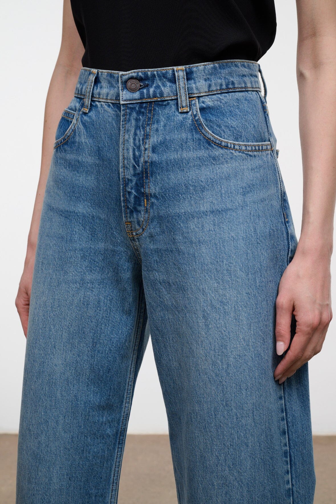 Blue high-rise denim jeans with button closure, belt loops, and front pockets.