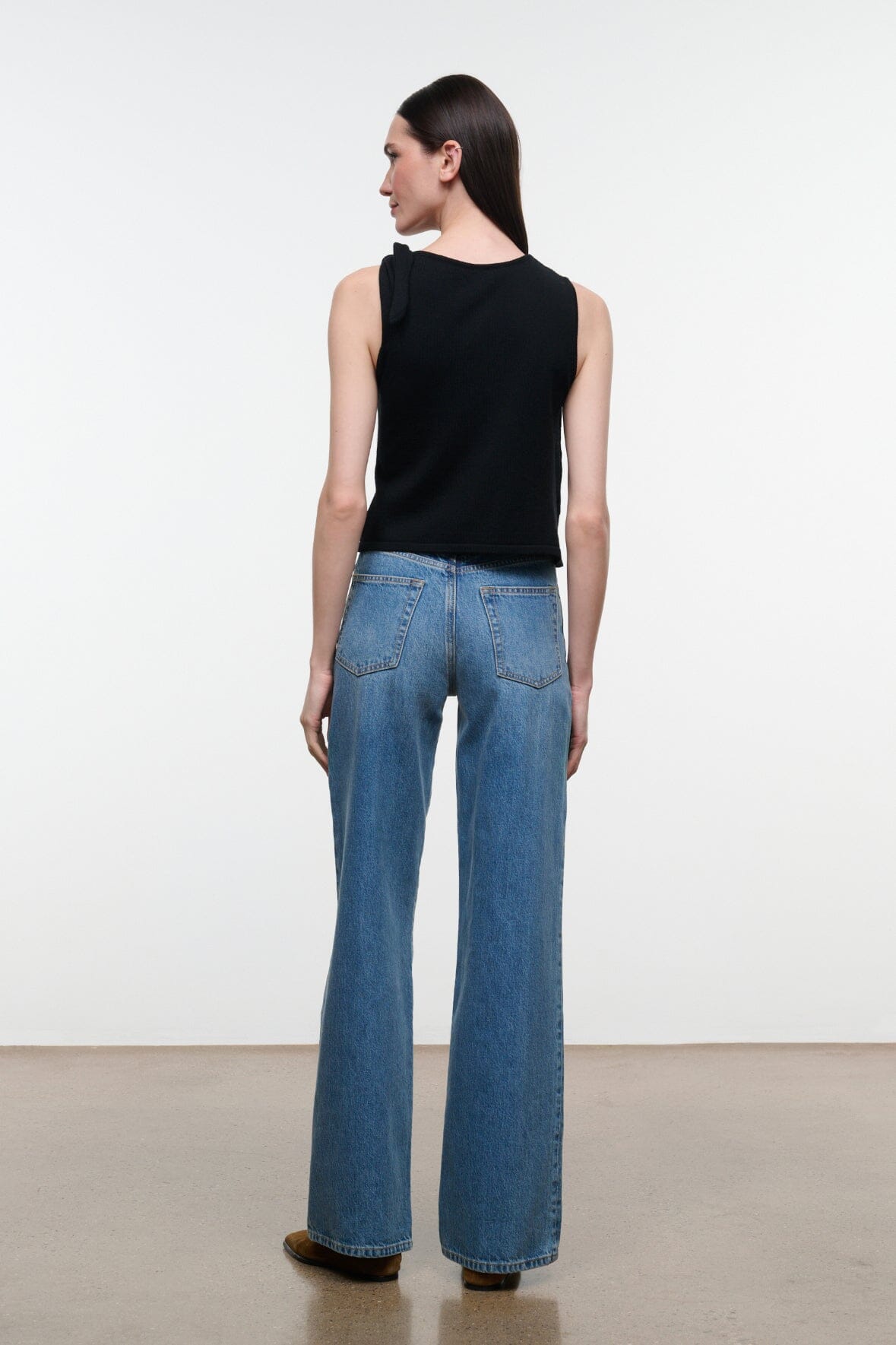 Back view of blue denim jeans with wide legs, belt loops, and rear yoke seaming