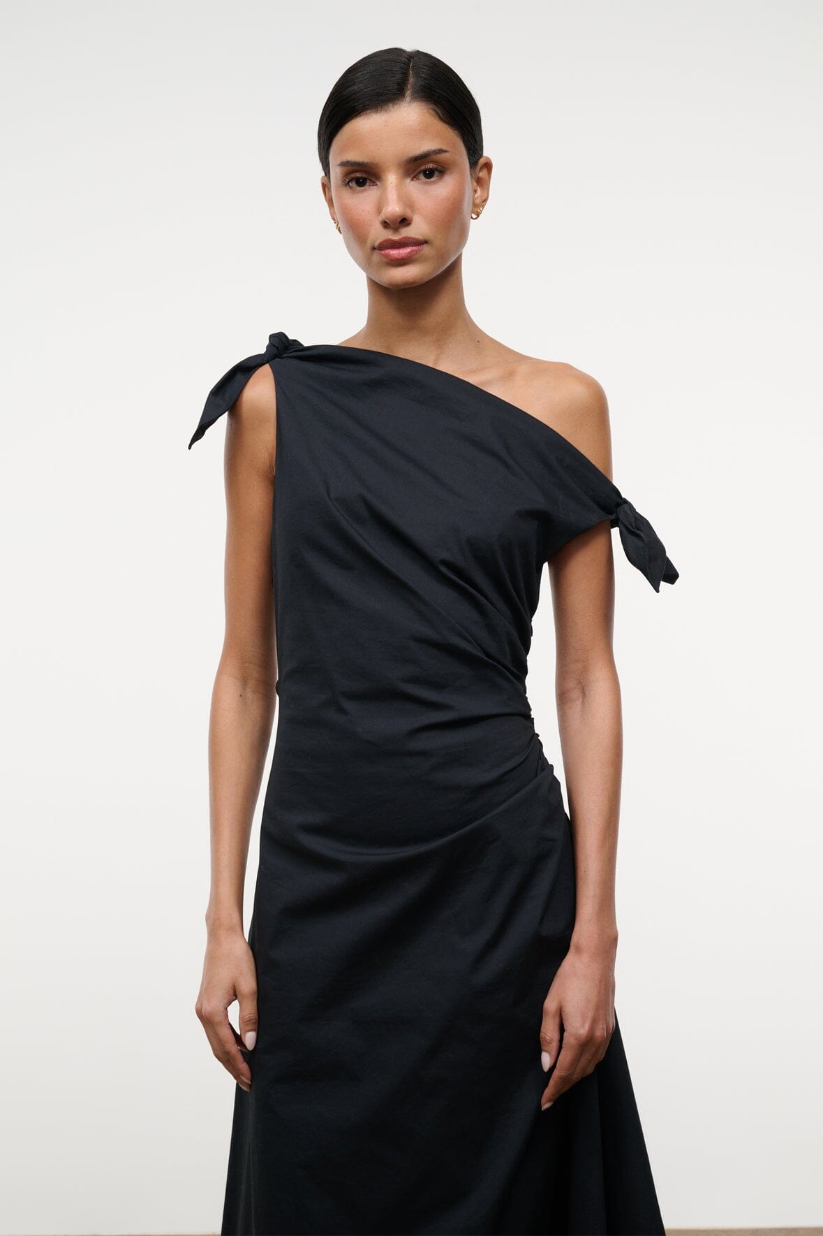Black one-shoulder midi dress with draped bodice and tied shoulder bow