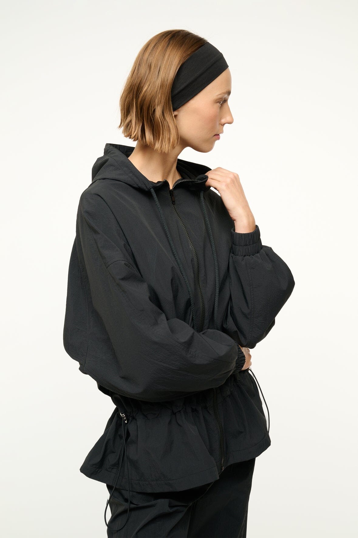 Black hooded jacket with zip front and drawstring hood; side pocket seams visible.