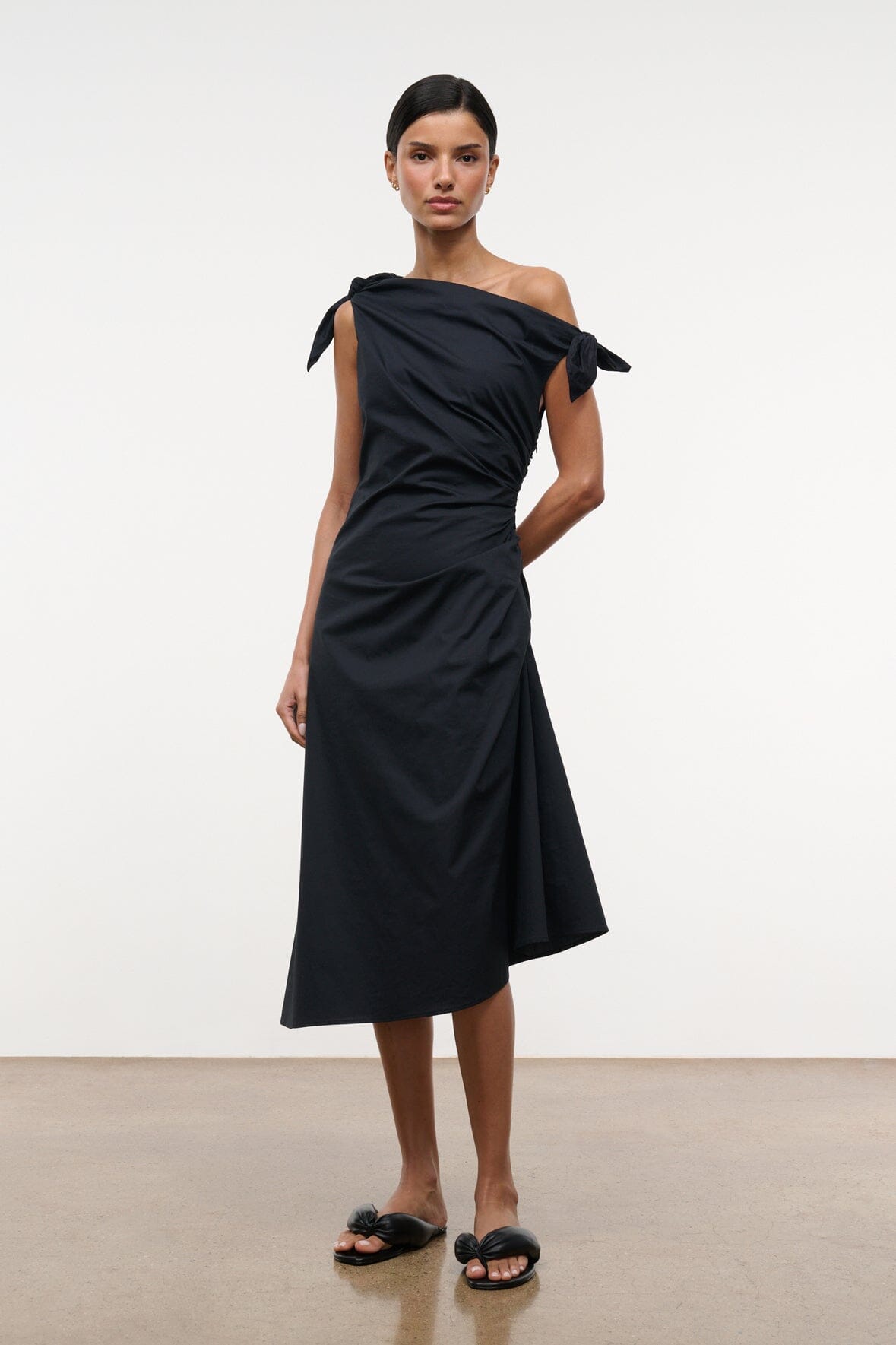 Black one-shoulder midi dress with tied shoulder bow and fitted waist