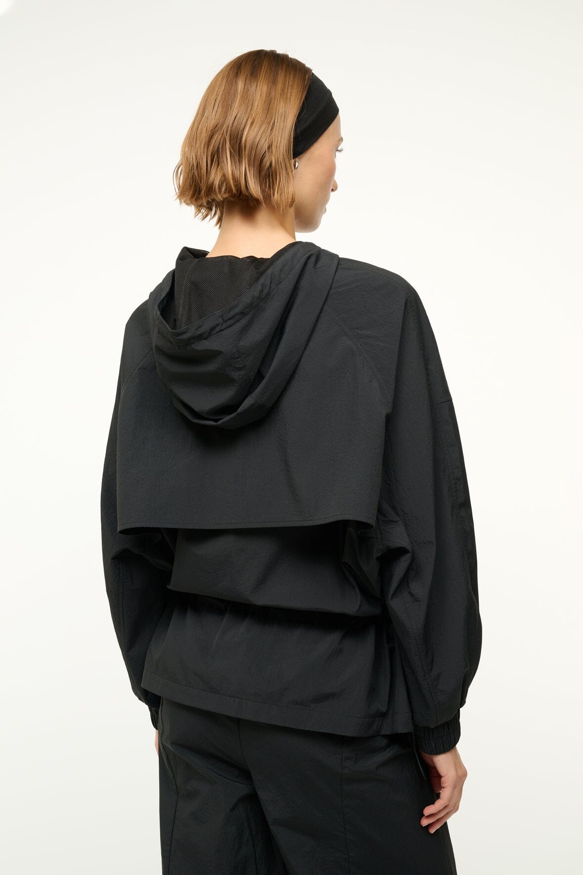 Black hooded jacket back view with gathered waist and elastic cuffs.