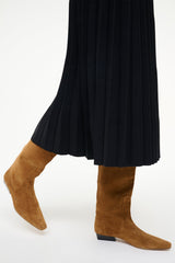 Tan suede flat knee-high boots worn with a black pleated dress
