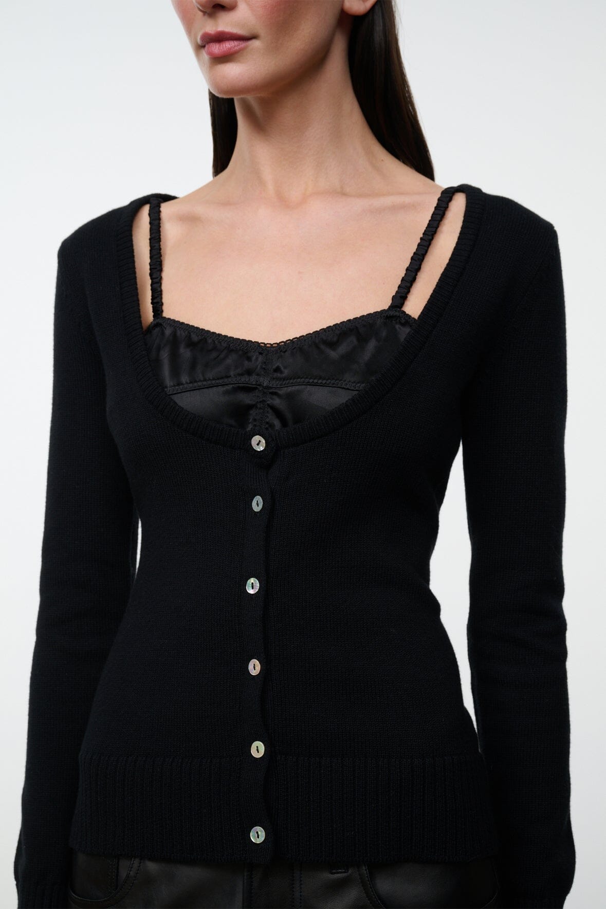 Black cashmere sweater close-up: square neckline, strap trim, metal-button placket