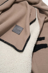 Truffle taupe throw blanket corner with black trim and small rectangular brand tag